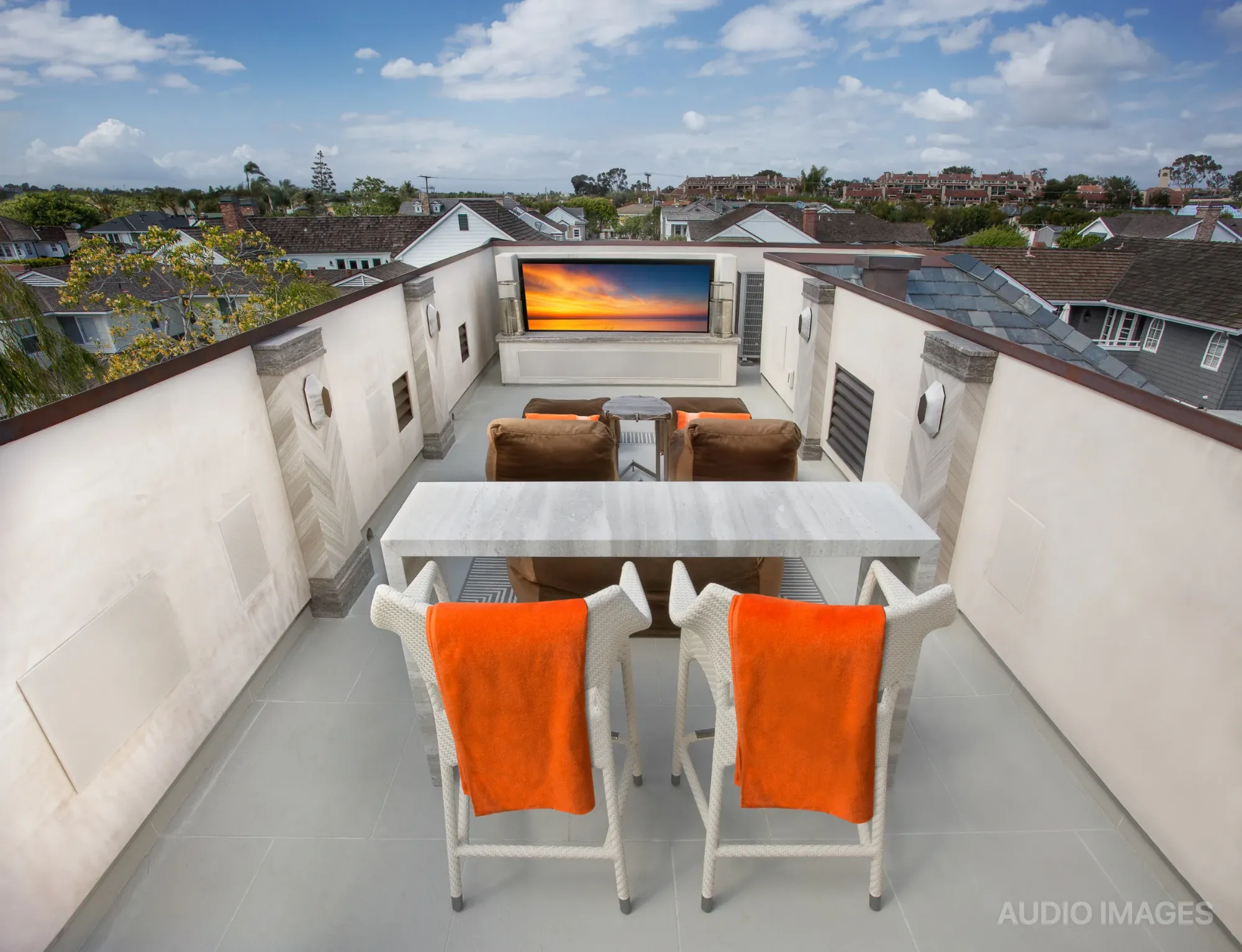 The rooftop seating area with the 84-inch outdoor television showing a sunset scene.