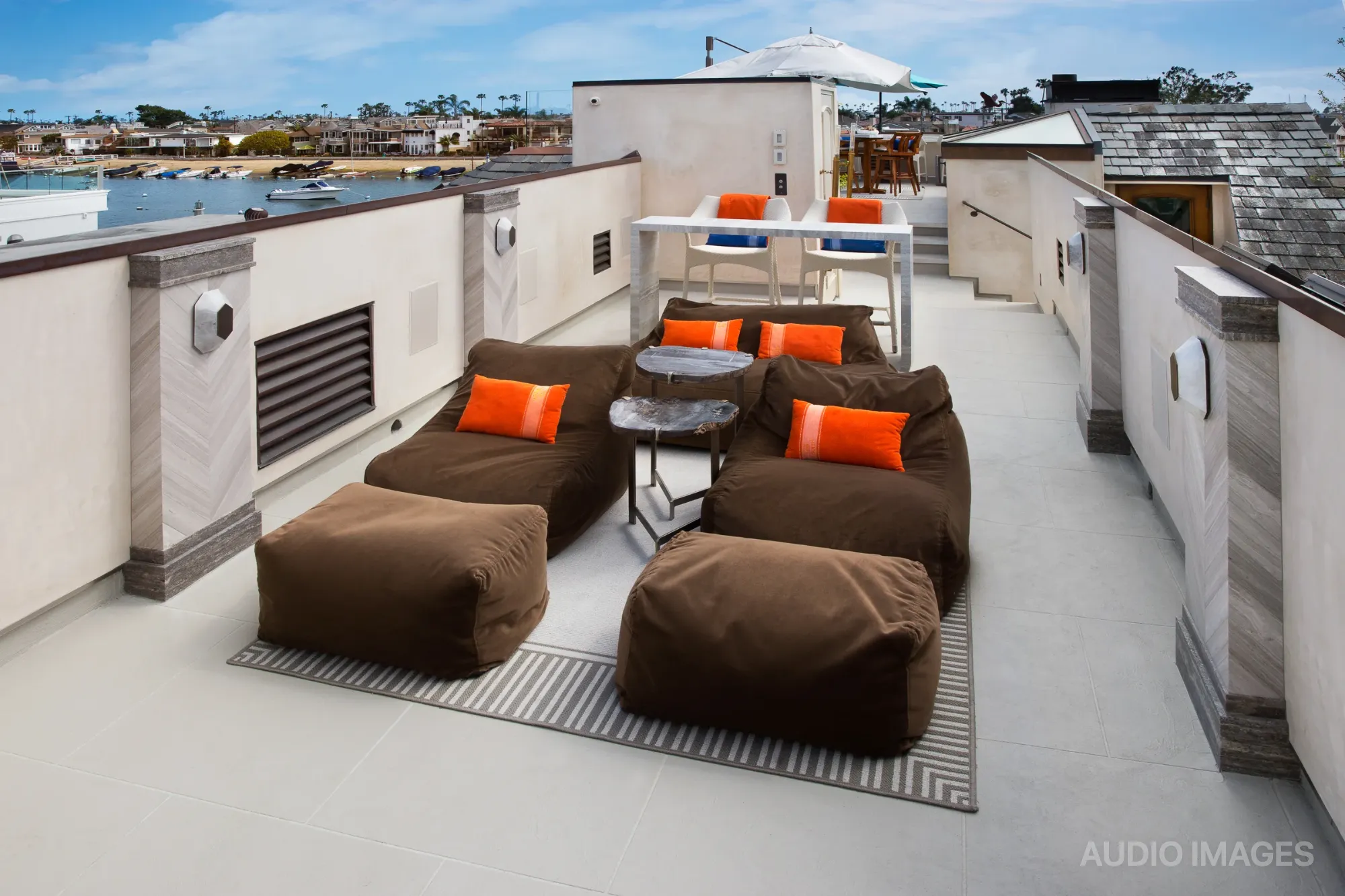 Rooftop living area with lounge seating, a bar table, and harbor views.