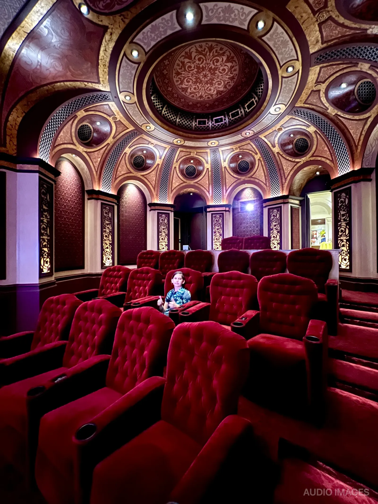 Child seated alone in the auditorium giving a thumbs up.