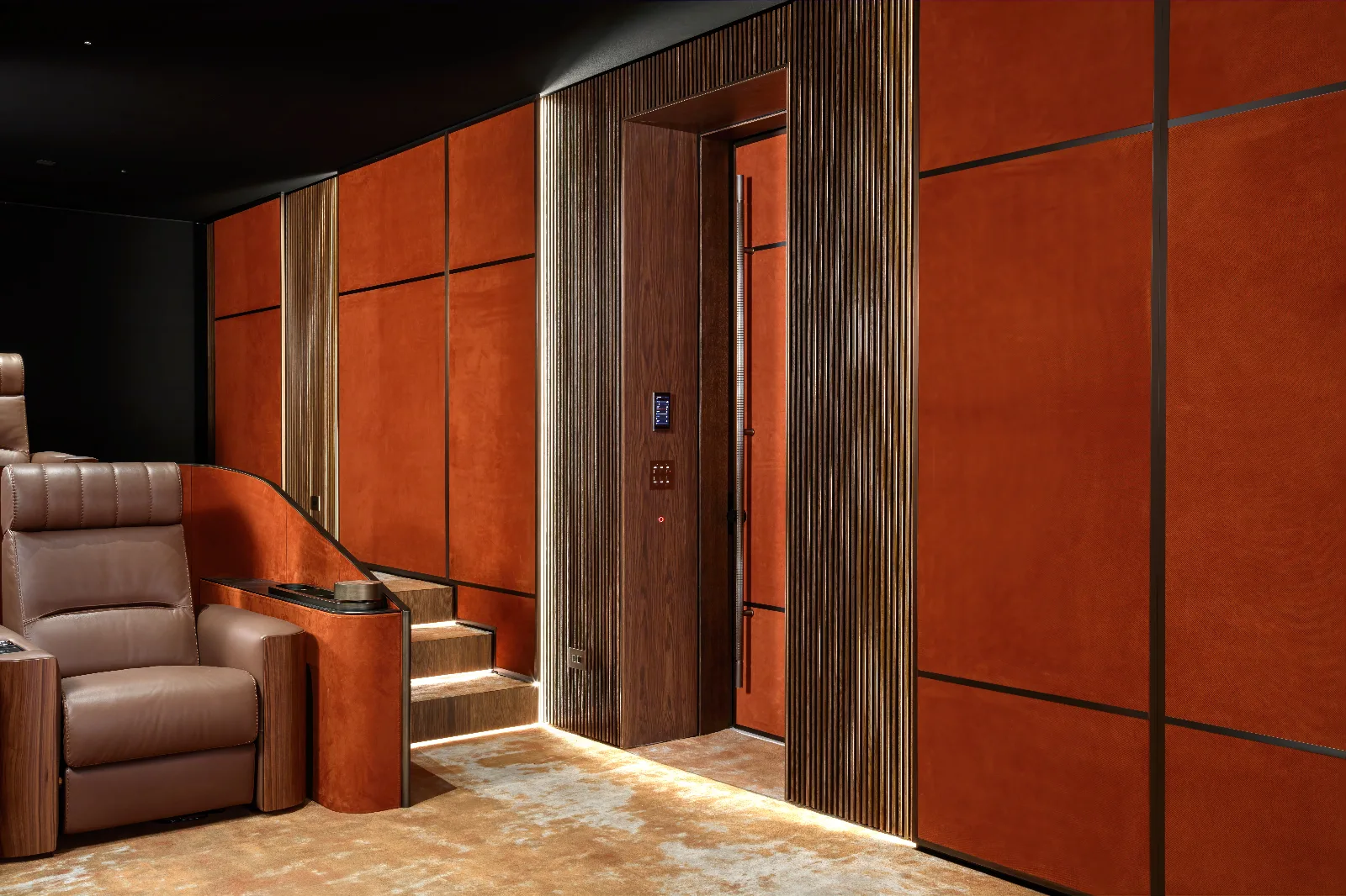 A home cinema features dark orange upholstered walls with illuminated wood paneling and a brown leather recliner.